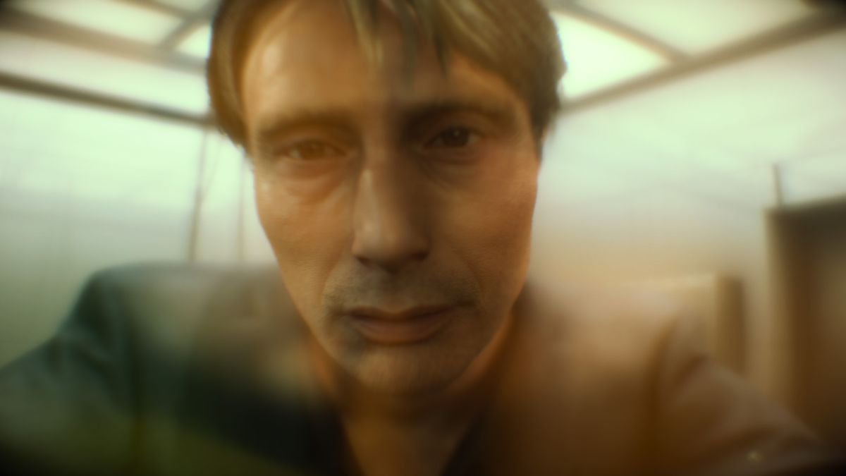 a close-up of a sad-looking man (Mads Mikkelsen) seen through an orange haze in Death Stranding