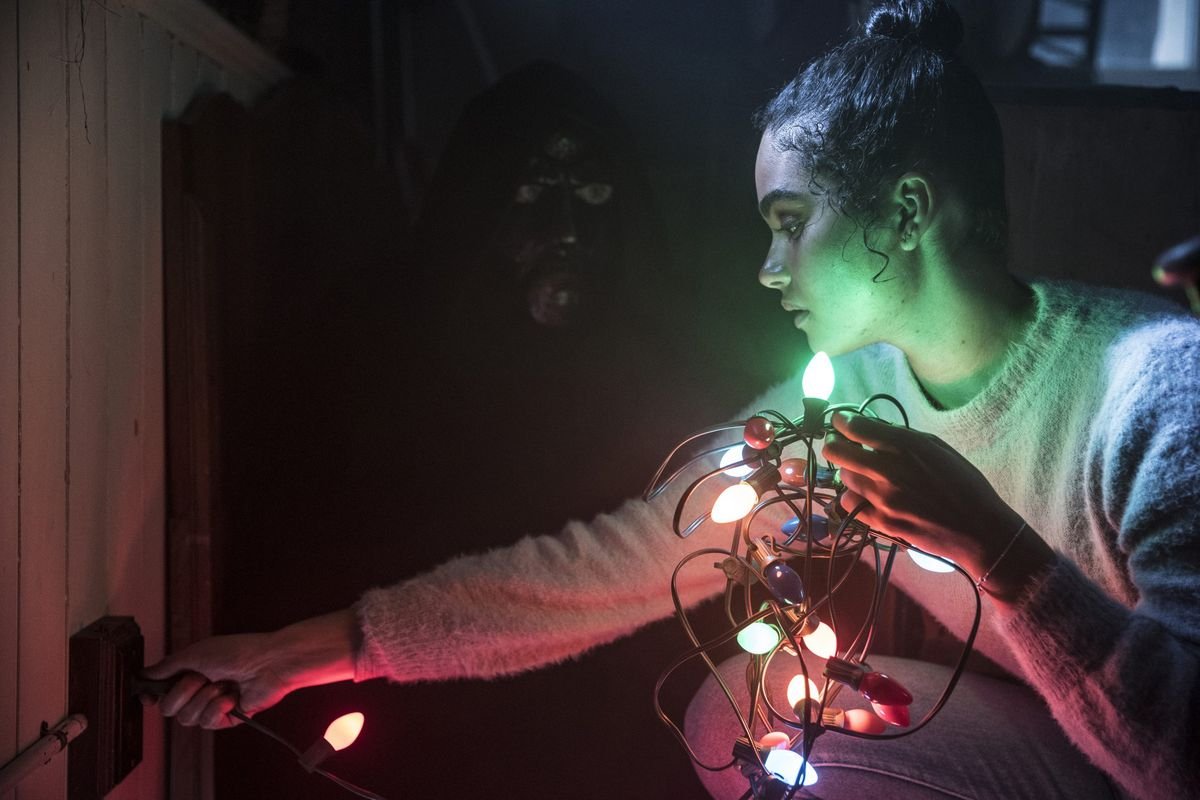 Jesse (O’Grady) tests a string of Christmas lights, illuminating a figure behind her.