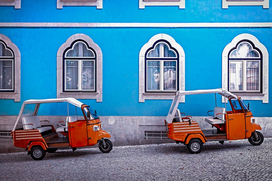 Tuk tuk vehicle in front of blue facade building in the Lisbon, Portugal.