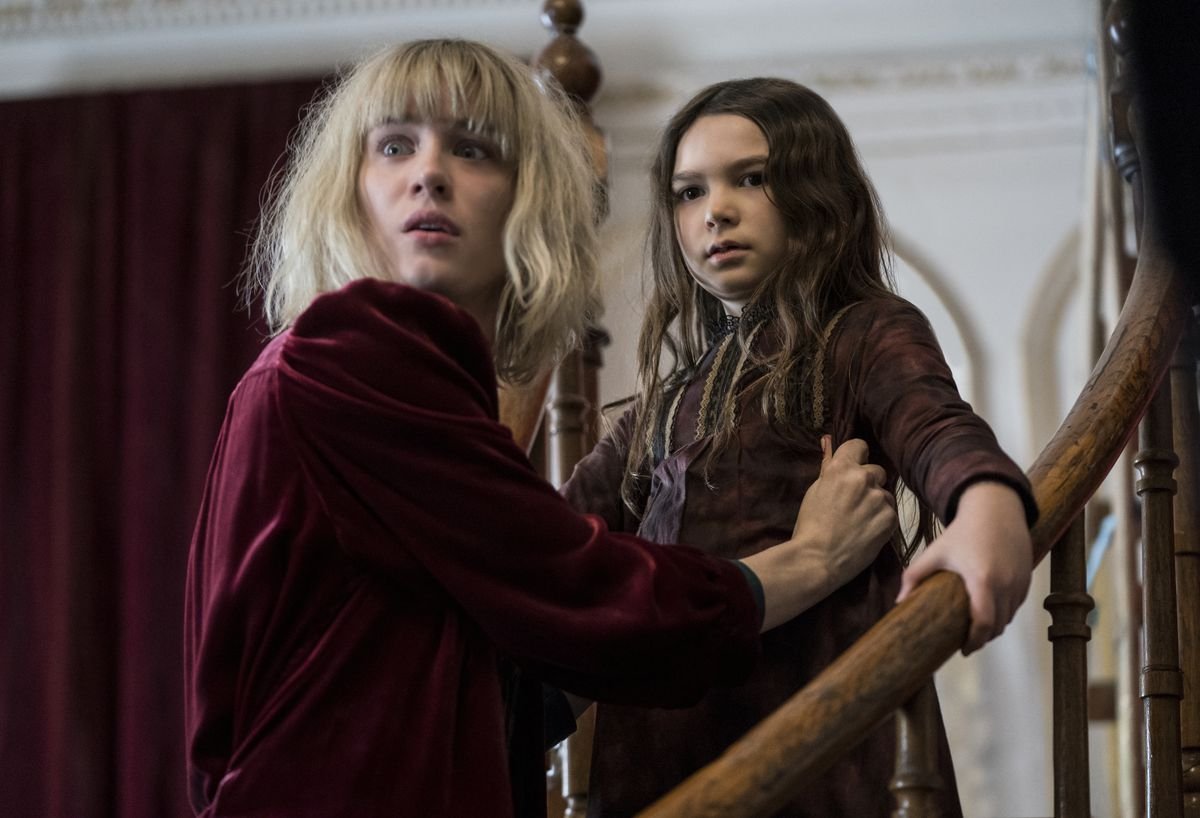 Kate Mandell (Mackenzie Davis) looks over her shoulder fearfully, while holding the younger Flora Fairchild (Brooklynn Prince) in “The Turning.”