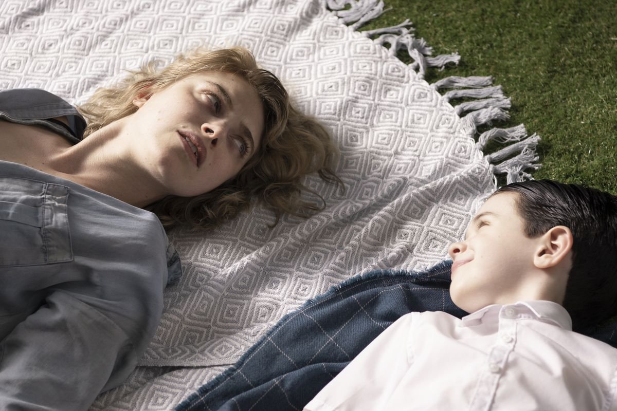 A woman looks at a child lying next to her.