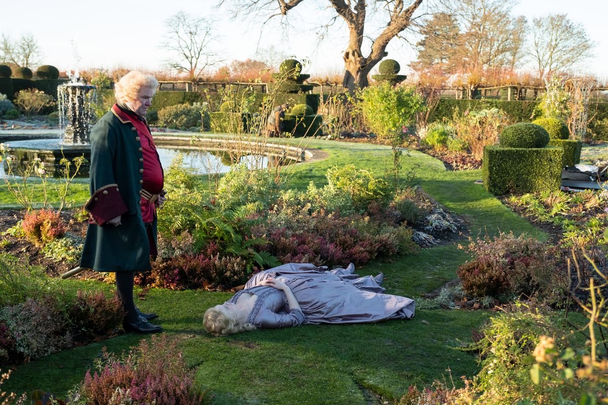 Catherine the Great flops on her back in an elaborate palace garden as a dubious courtier looks on.