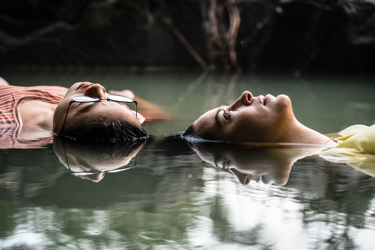 two young women float in water