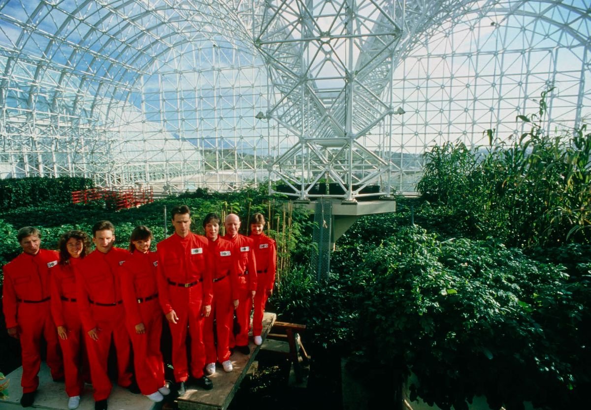 seven men and women in red suits in the Biosphere 2 in a still from the documentary Spaceship Earth