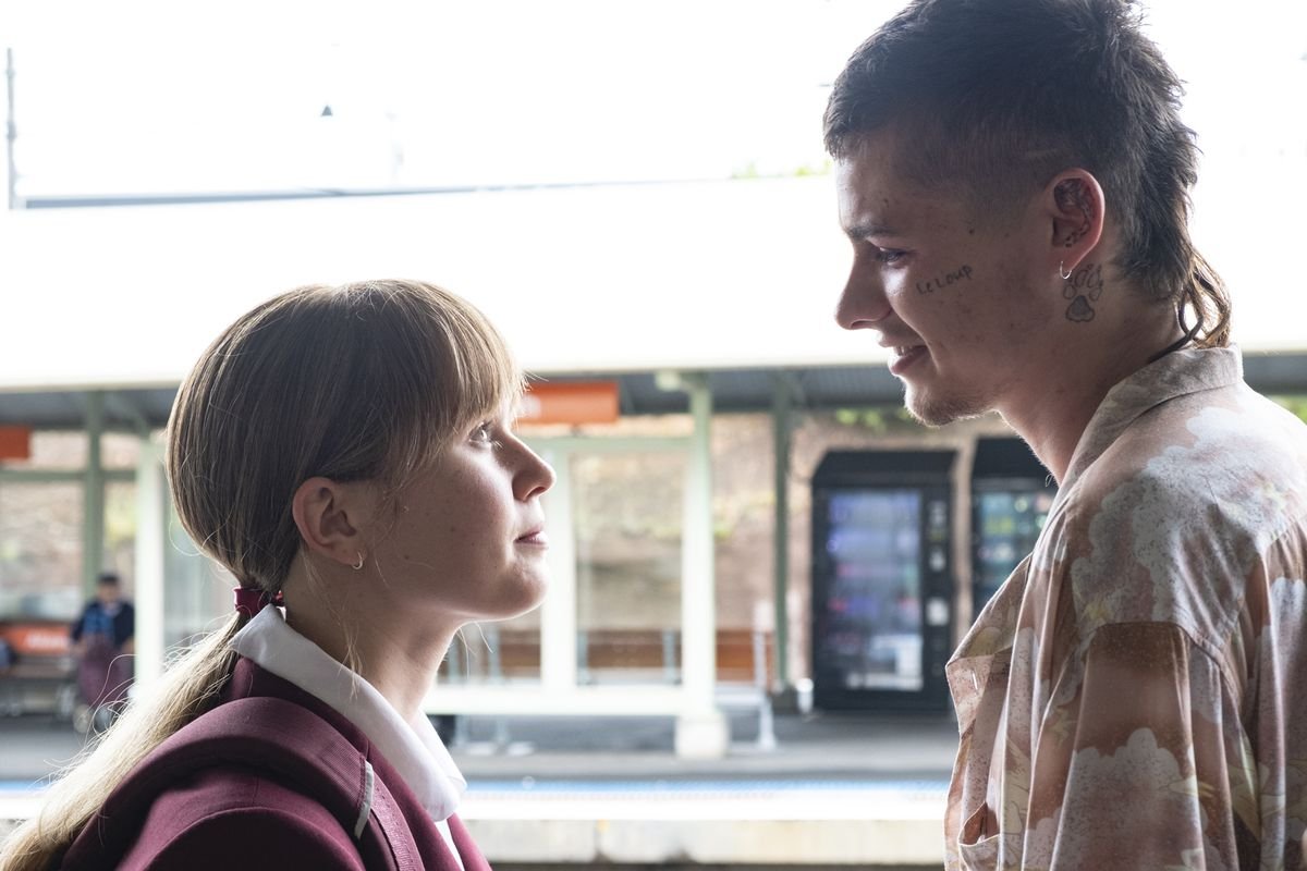 a young woman and a young man look at each other