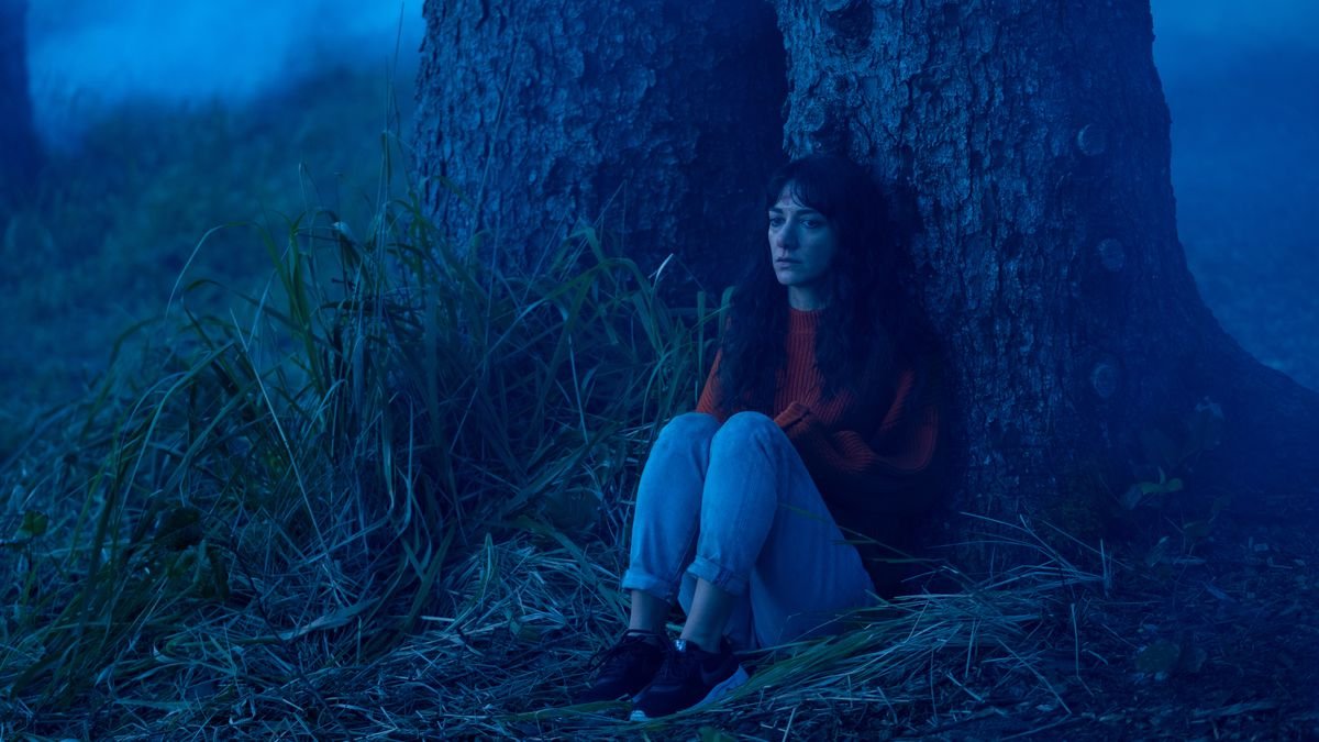 Sheila Vand sits glumly under a tree in Dave Franco’s The Rental.