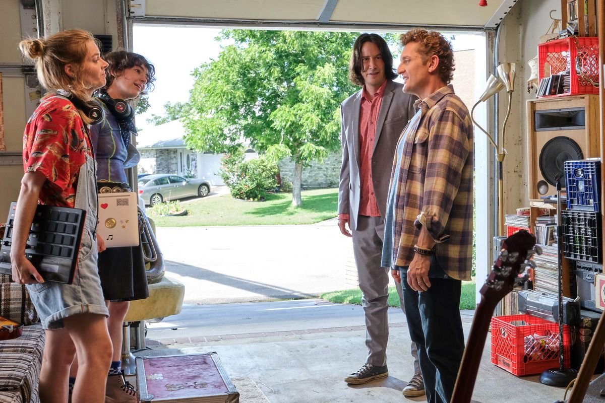 two young women and their fathers stand in a garage