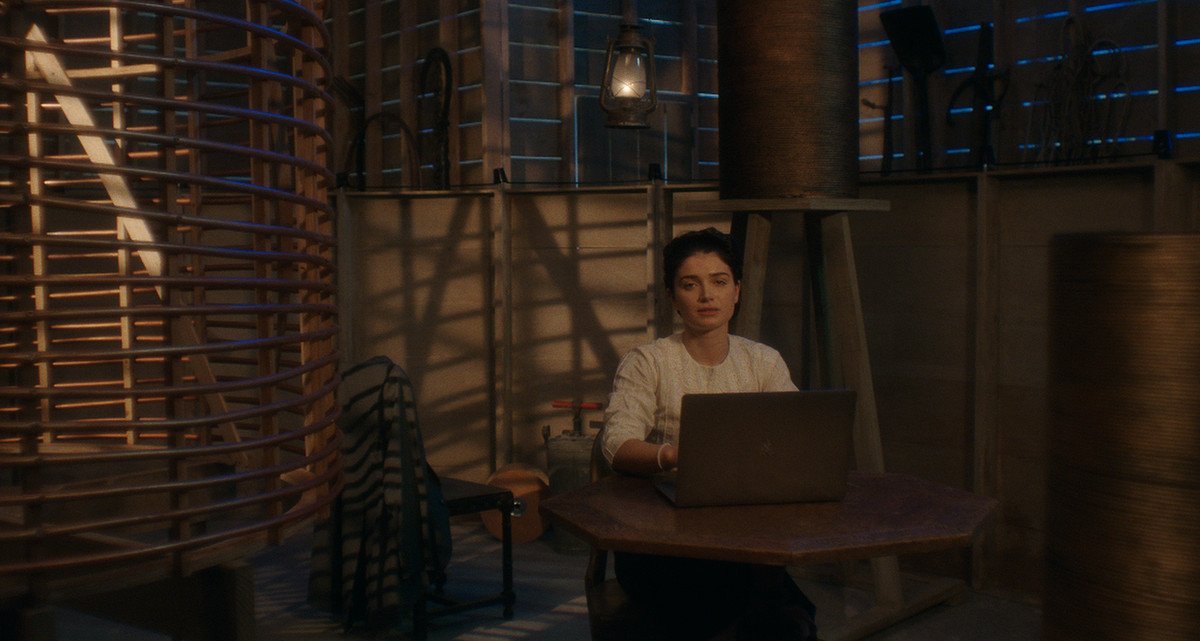 a woman sits behind a laptop