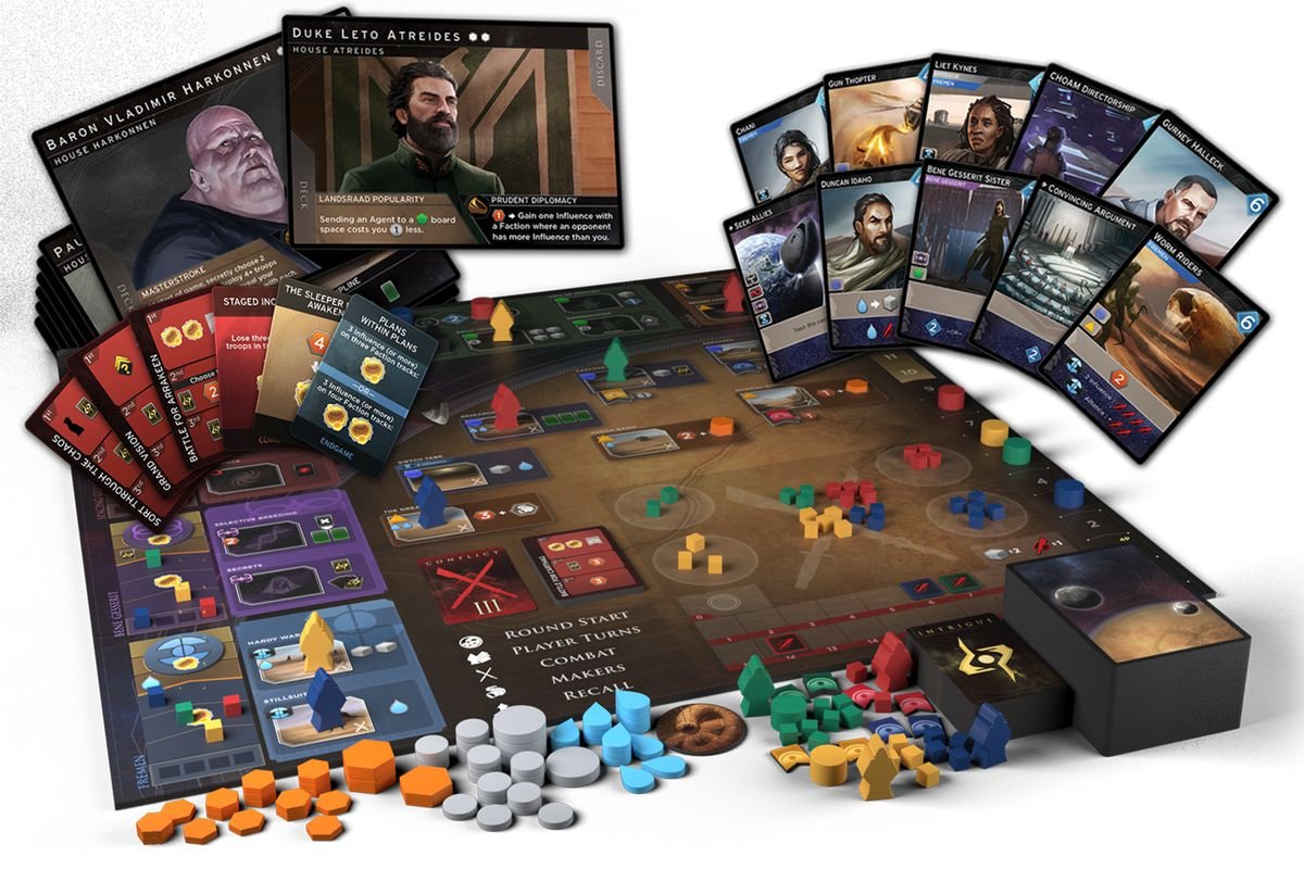 A game board with a fan of cards above it. In the foreground is a pile of multi-colored wooden pieces.