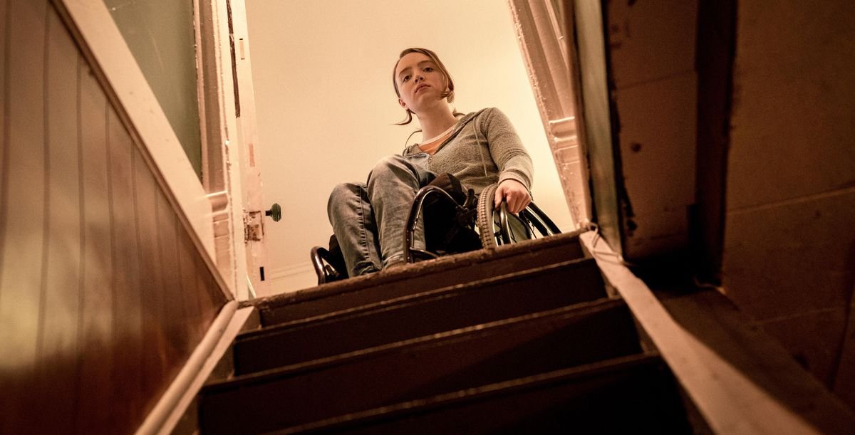 Kiera Allen, in a wheelchair, pauses at the top of a darkened staircase in Hulu’s Run