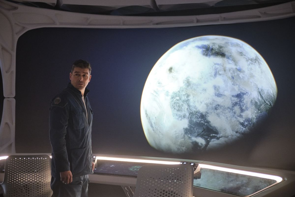 Kyle Chandler looks out a window at a planet in The Midnight Sky