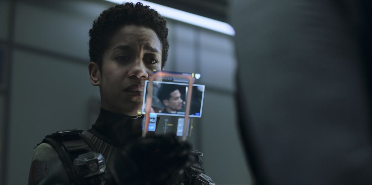 Naomi Nagata, played by Dominque Tipper, looks at a high-tech handheld photo display with apparent distress in The Expanse