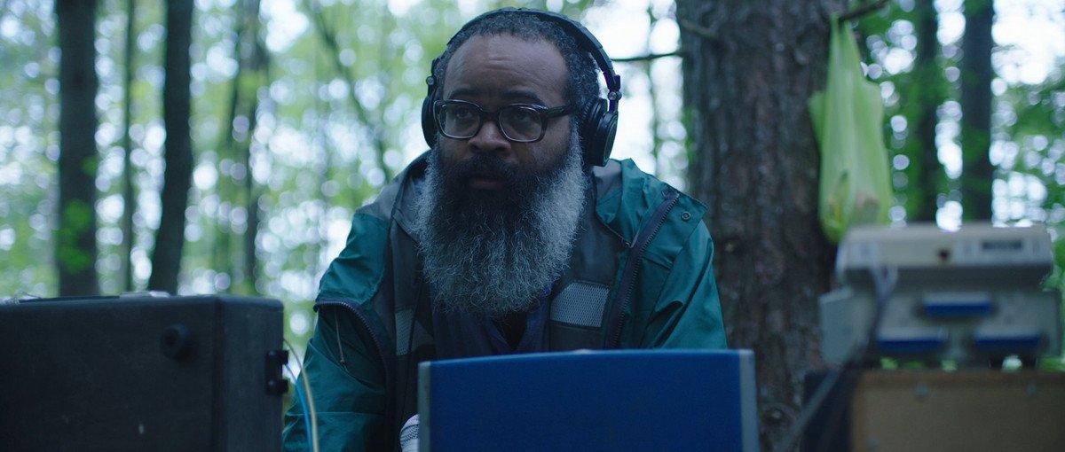 Kyp Malone, sporting headphones and a major beard, attempts to talk to a door in Doors