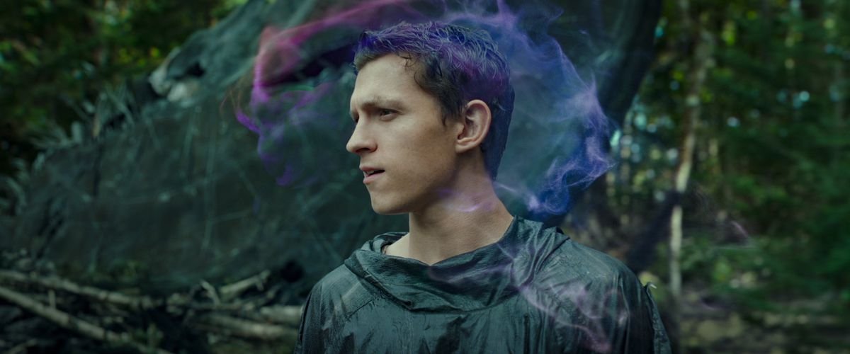 Todd (Tom Holland) looks around a forest while a wispy cloud of purple and pink swirls around his head in Chaos Walking