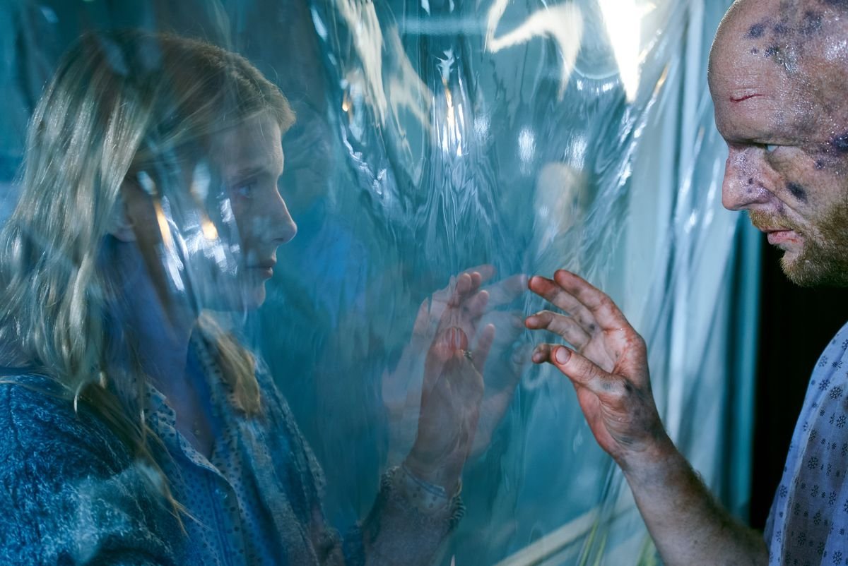 Mélanie Laurent reaches her hand toward a wounded, dirty man on the other side of a sheet of plastic in Oxygen