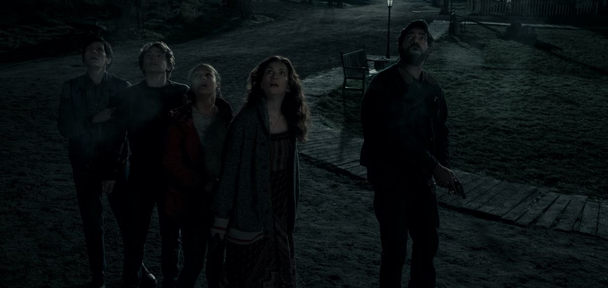 A group of people walking on a dark nighttime path gape upward together in Midnight Mass