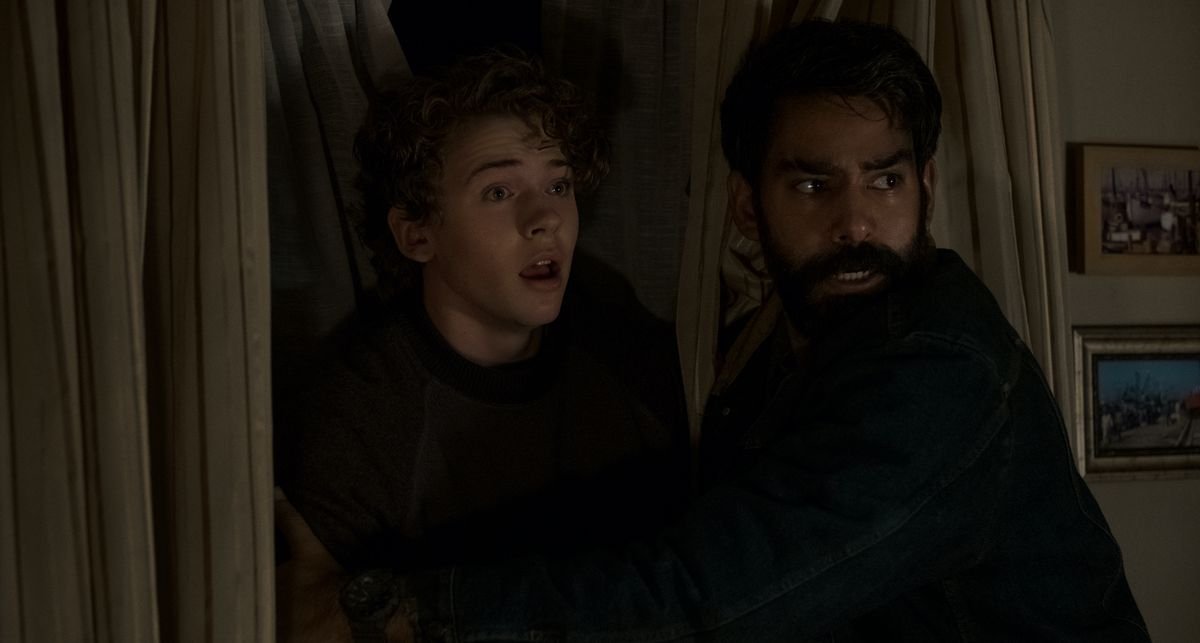 An older man and a teenager back against a wall, looking alarmed, in Midnight Mass