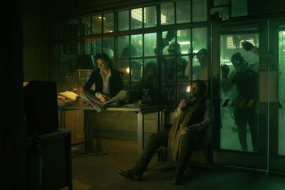 Two members of the Doom Patrol sit in a darkened room together while others press up against the outside of the glass wall behind them in Doom Patrol season 3