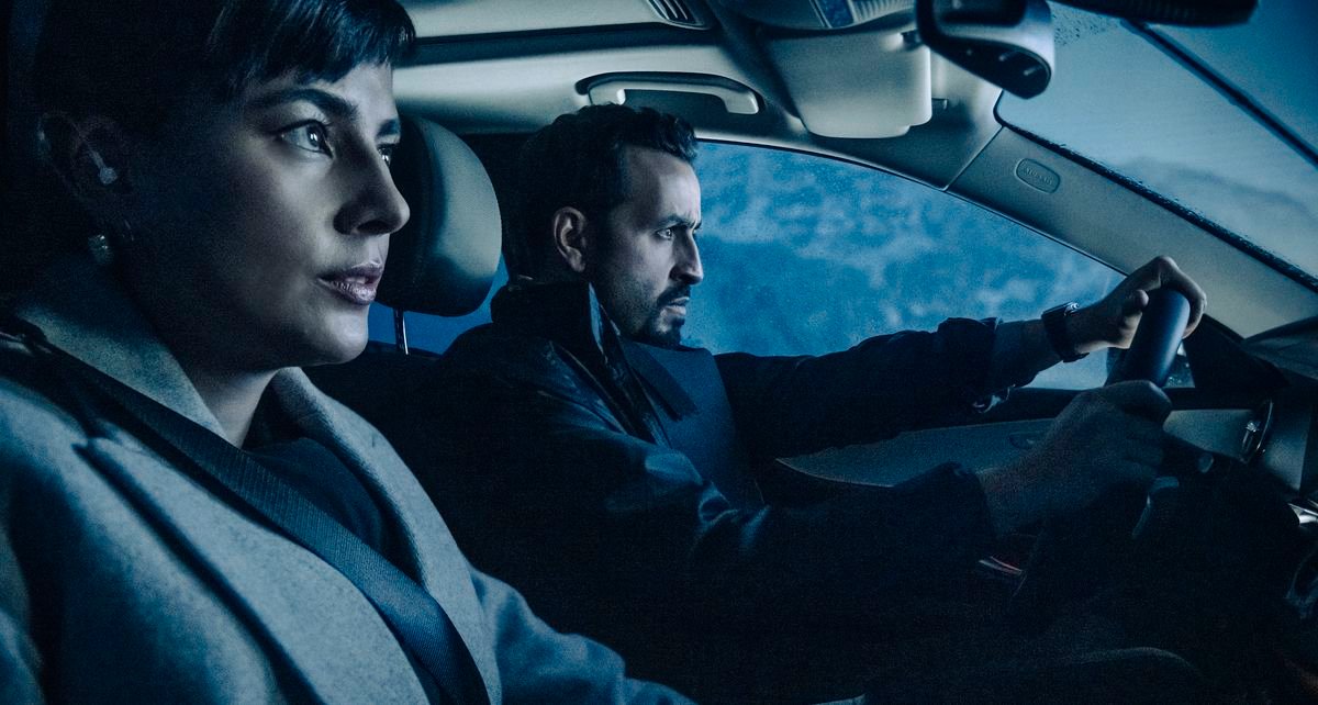 Noemie Nakai as Beatrix and Jonathan Cohen as Delacroix sit in a car together in blue light in Army of Thieves