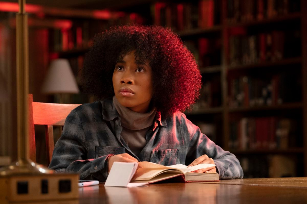 Zoe Renee as Jasmine sits at a table in a student library