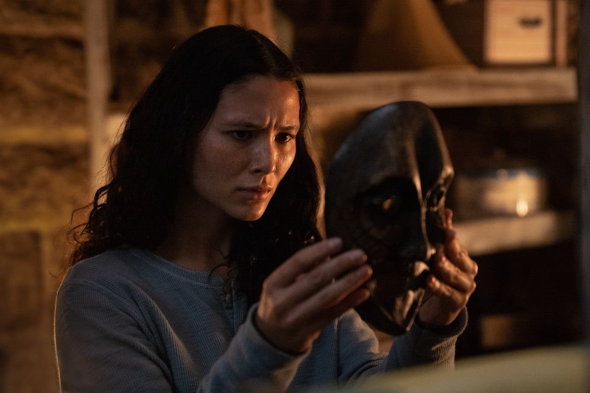 Fivel Stewart holds up a creepy mask and stares at it in the horror movie Umma