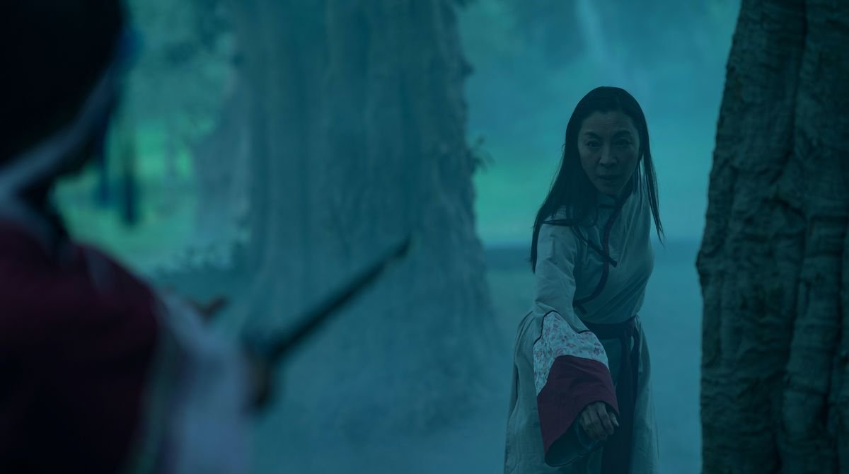 Michelle Yeoh, in period hanfu dress, backs into a forest as an off-screen assailant points a sword at her in Everything Everywhere All at Once