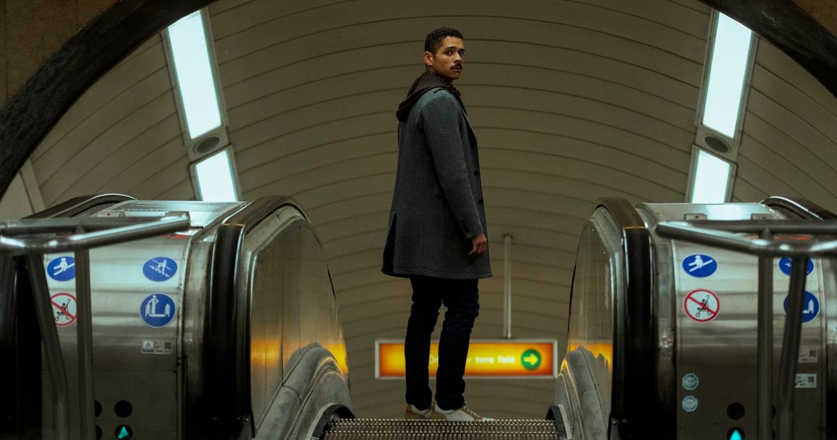Alan standing on an escalator in a subway station