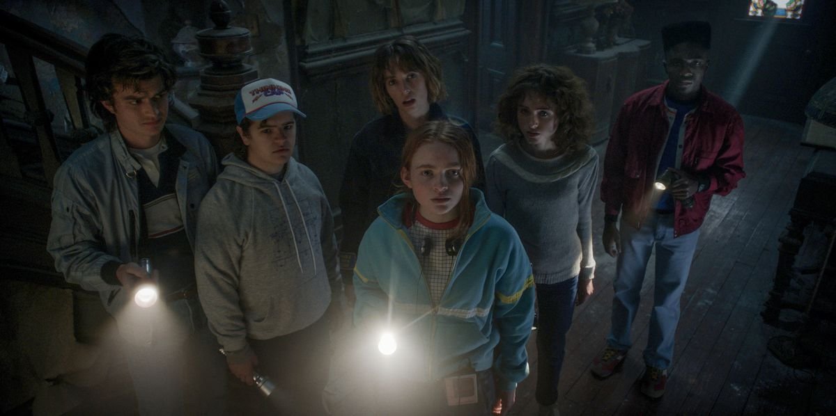 The Hawkins gang in Stranger Things season 4 looking towards the camera in a haunted house