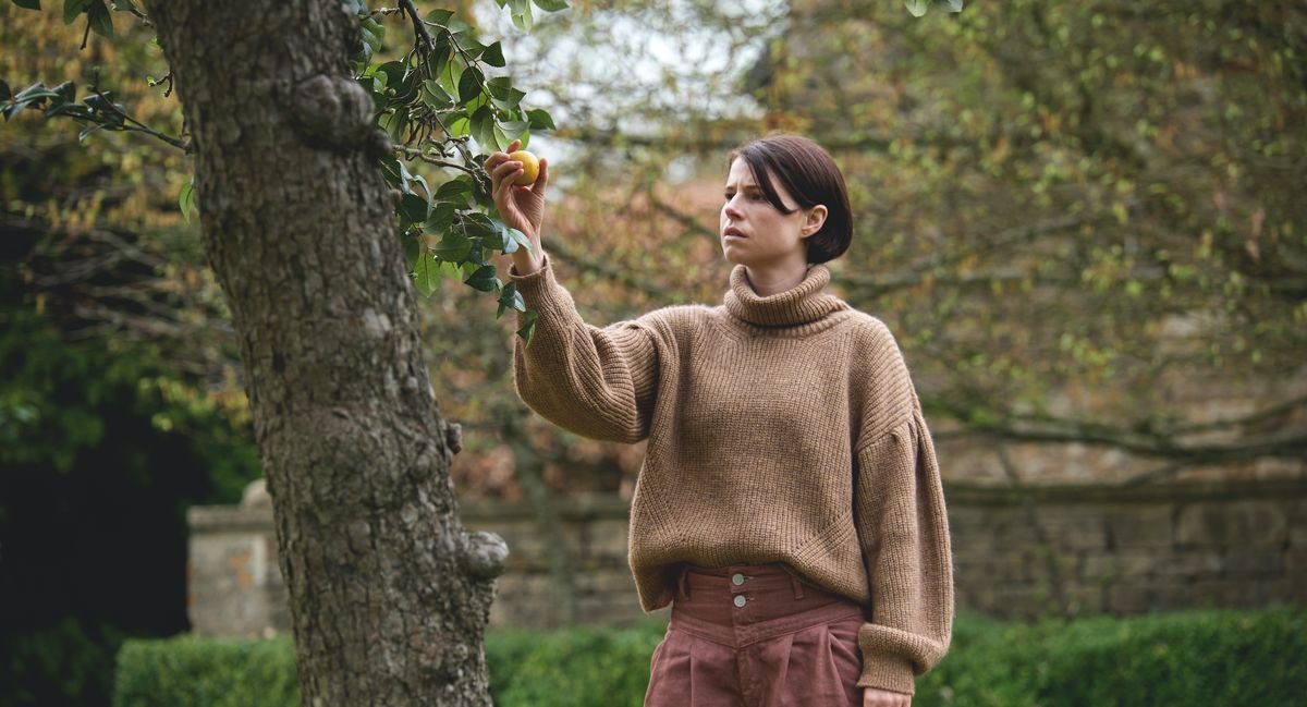 Jessie Buckley picks a highly symbolic apple from a tree in Alex Garland’s Men.