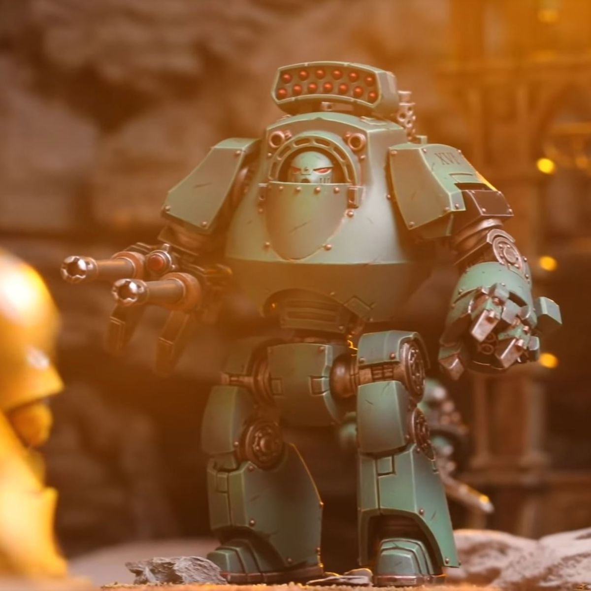 A Contemptor pattern dreadnaught stands above the battlefield, painted a light green of the Sons of Horus.