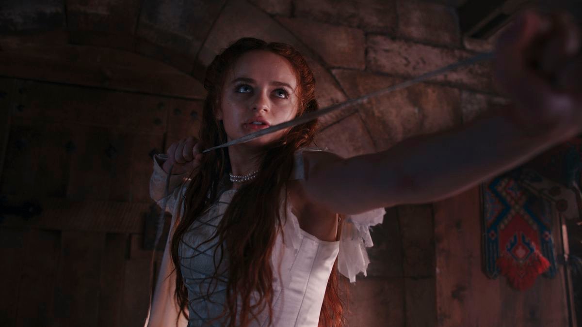 the princess, as played by joey king, in a ripped white dress holding a whip