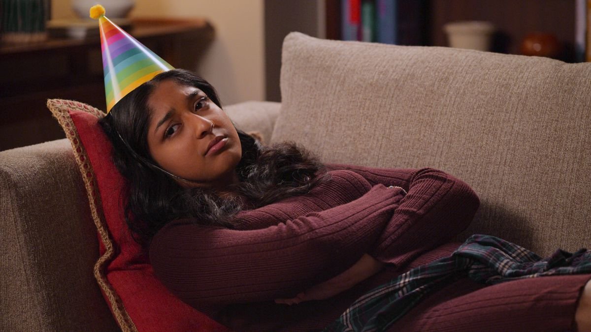 devi slumped in a chair, a party hat on her head