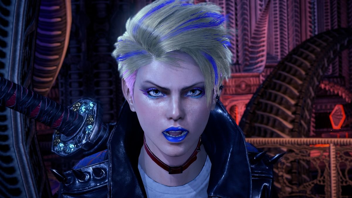 Viola, a witch in training who makes her first appearance in Bayonetta 3, faces the camera for a close-up shot that shows off her colorful blue lipstick, pink and blue eye makeup, and short blond haircut with purple streaks