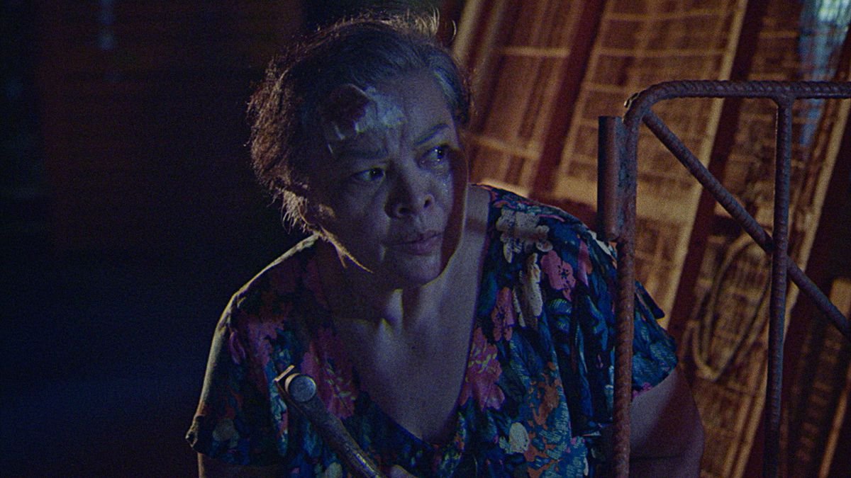 Leonor (Sheila Francisco), an elderly Filipina with a bloody bandage on her head, lurks outside at night looking suspicious in Leonor Will Never Die
