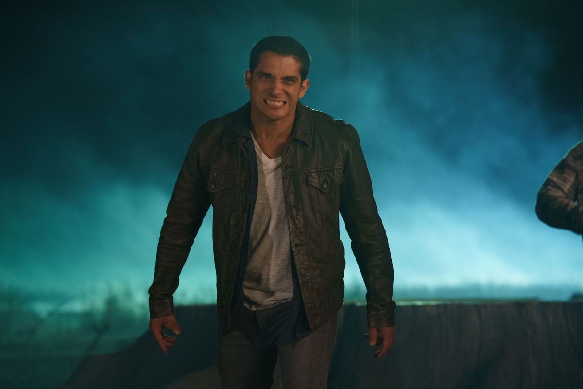 Tyler Posey as Scott McCall growing with his eyes squinted with fog and bright light lighting up the night behind him in Teen Wolf: The Movie