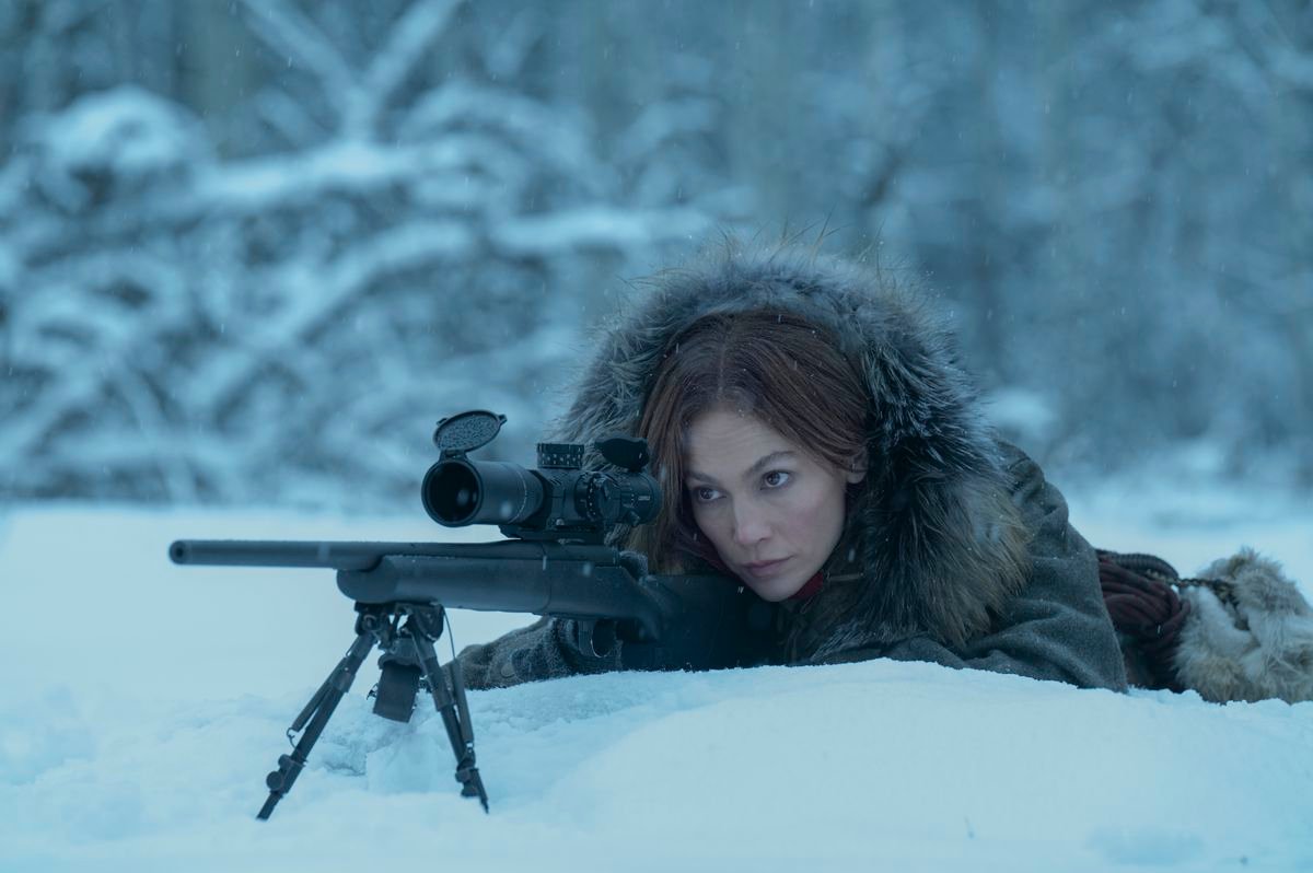 Jennifer Lopez lies down with a sniper rifle in the snow, with a heavy fur coat on, in The Mother.