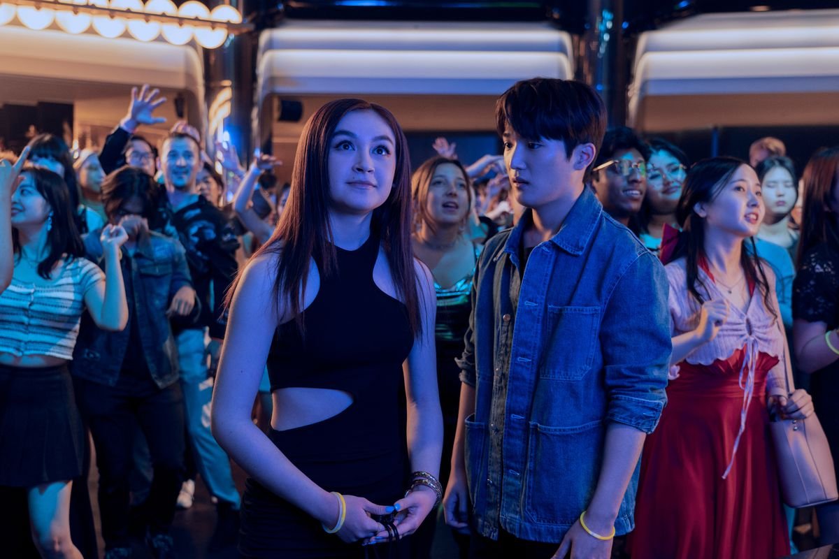 Kitty, a half-Asian teenage girl, wears a cute black cutout dress while in a nightclub. Dae looks longingly at her. 