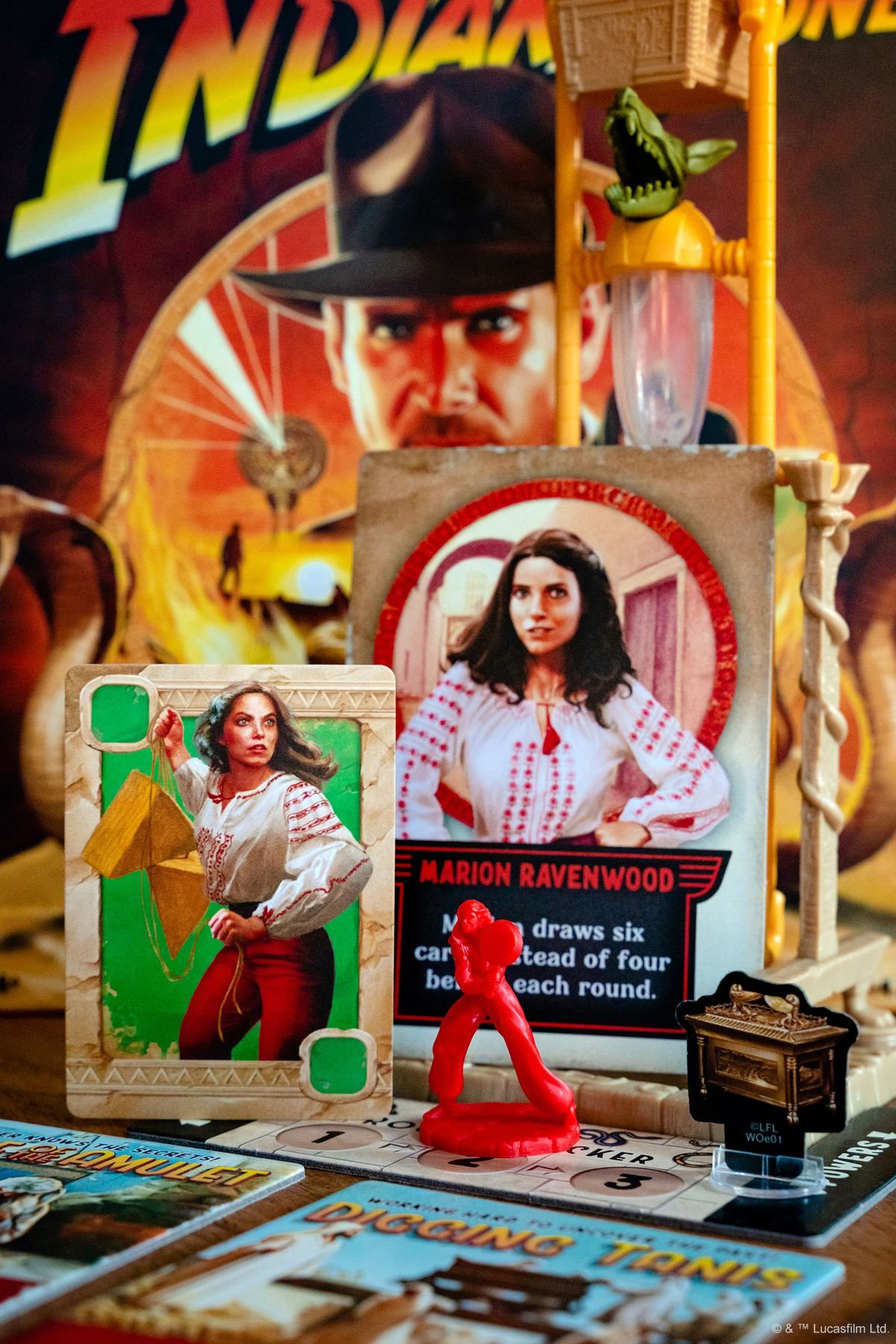 A card for Marion Ravenwood, and a red miniature. The image also shows a cardboard mover in the shape of 