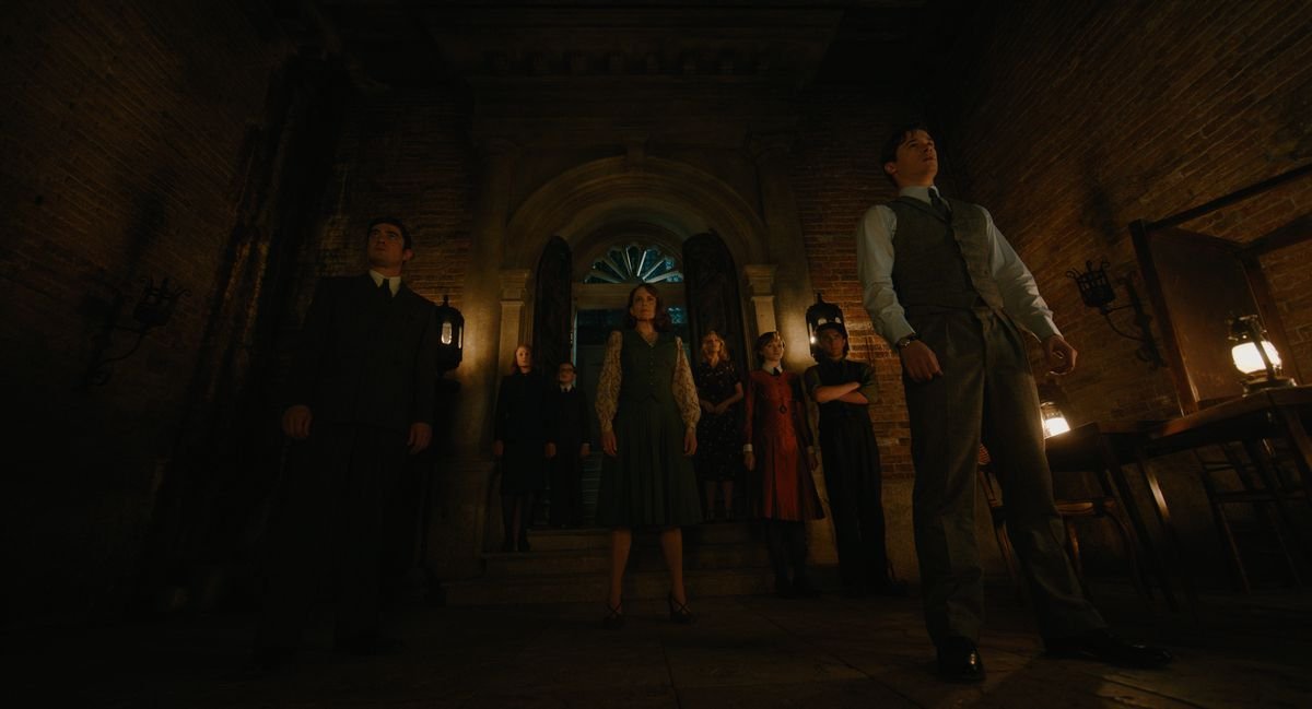 A shot of a group of strangers as viewed from below. They stand in an eerie Venetian mansion.