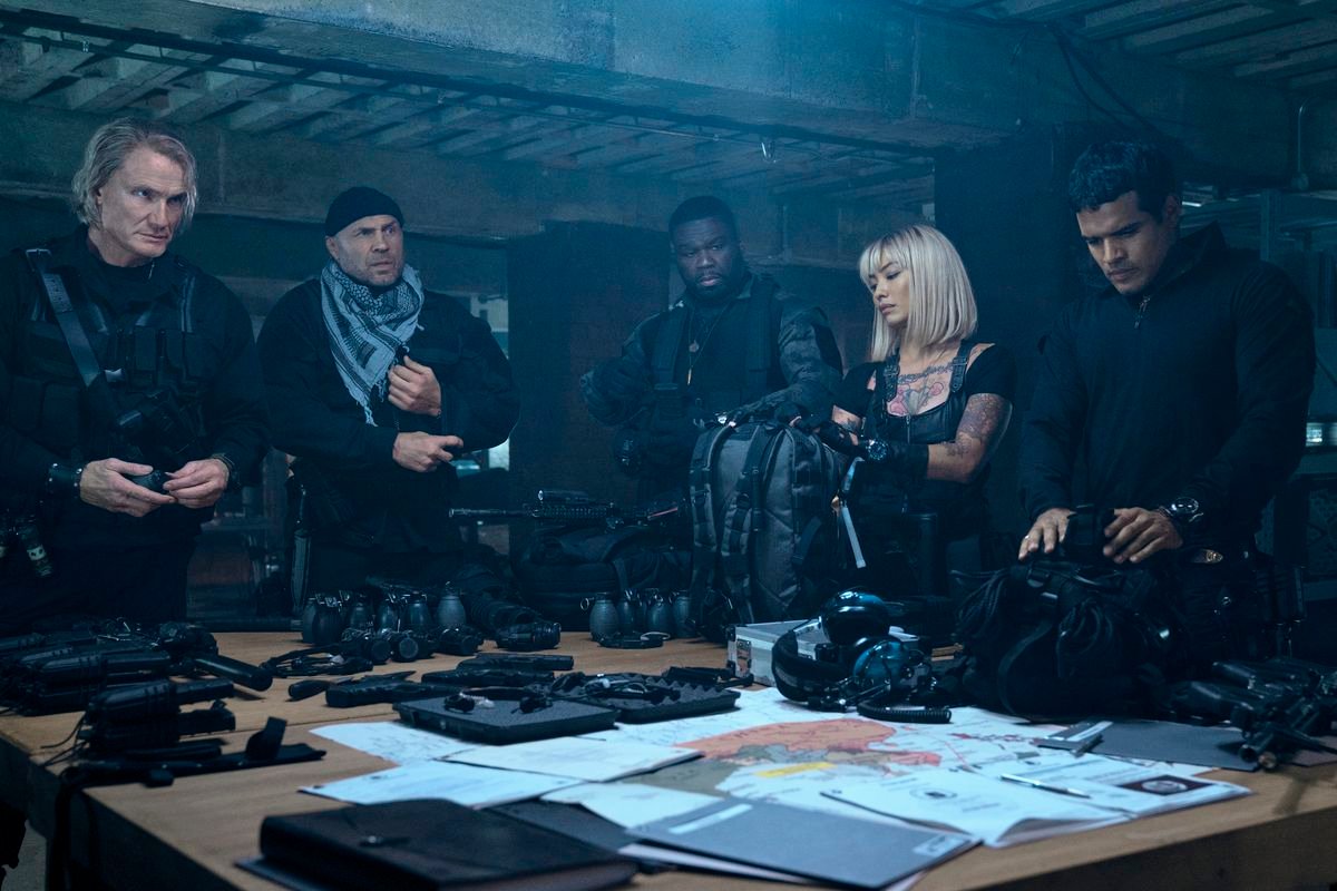 Some of the Expendables circa Expend4bles gather around a table full of gear and plans: Gunner Jensen, Toll Road, Easy Day, Lash, and Galan.
