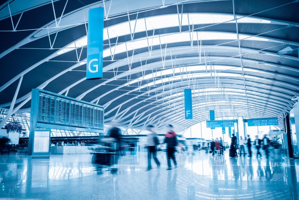 Blurry images of people walking through a large central airport terminal