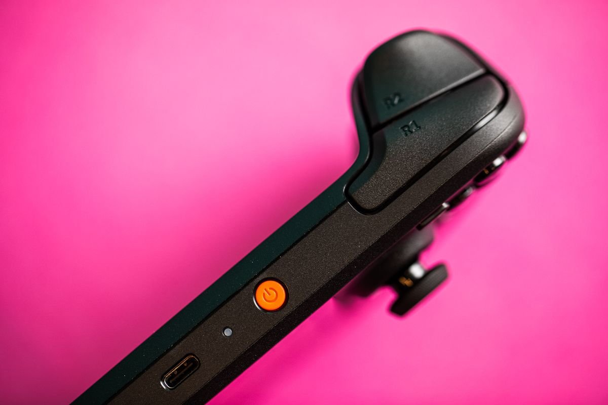 Photographs of the Steam Deck OLED, and of its hard zip-up case. Each photo is taken with the handheld sitting on a hot pink sheet of thick paper.