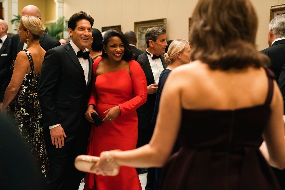 Aunjanue Ellis-Taylor and Jon Bernthal smile in evening dress at a fancy social gathering in Origin