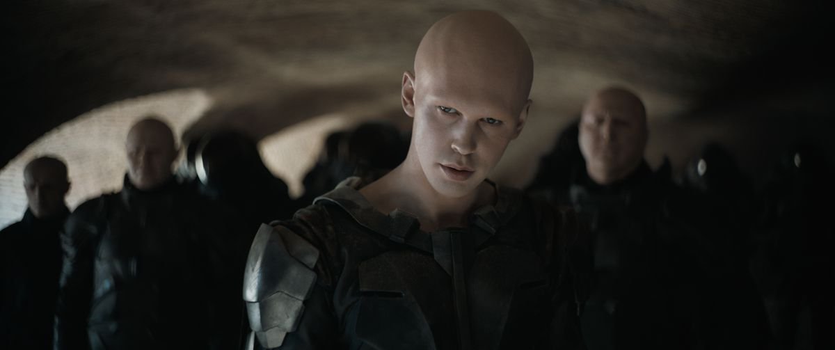 Austin Butler as Feyd-Rautha Harkonnen wearing all black with a group of soldiers behind him in Dune: Part Two