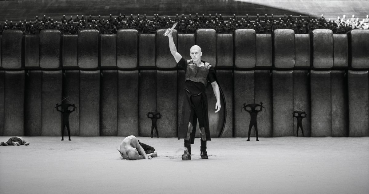 Austin Butler as Feyd-Rautha Harkonnen in Dune: Part Two holding a knife over his head in an arena in black and white