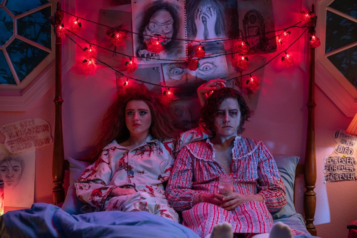 Lisa and the Creature sit side-by-side on her bed.