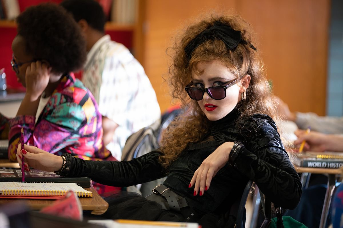 Lisa in a sick black ensemble, looking badass while sitting in class