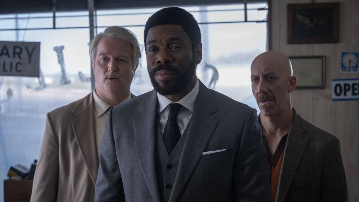 Colman Domingo as The Chief and his two henchmen stand in an auto garage in a scene from Drive-Away Dolls.