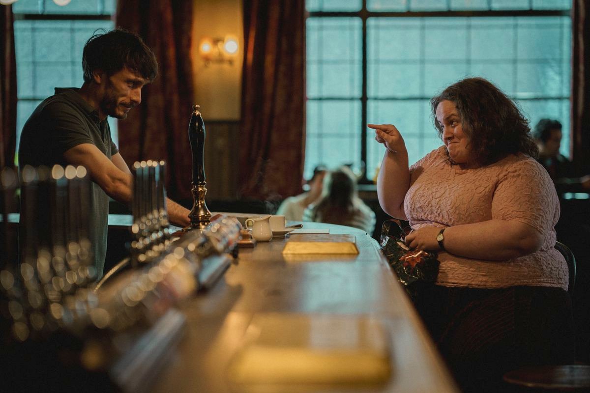 Richard Gadd and Jessica Gunning look at each other across the bar in a pub in Baby Reindeer. She’s pointing at him and smiling