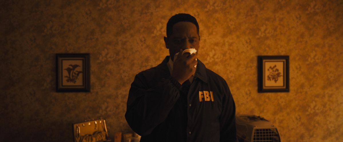 Blair Underwood as Agent Carter in Longlegs holding a cloth up to his nose and looking toward a crime scene that’s off-screen
